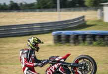 Ducati Hypermotard 950 stunt rider performing wheelie on racetrack wallpaper