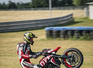 Ducati Hypermotard 950 stunt rider performing wheelie on racetrack wallpaper
