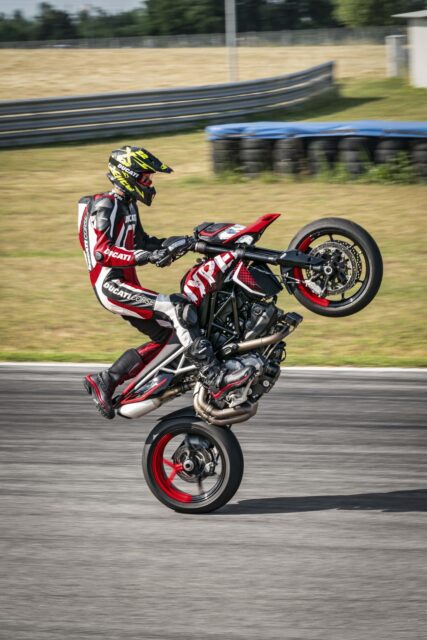 Ducati Hypermotard 950 stunt rider performing wheelie on racetrack wallpaper
