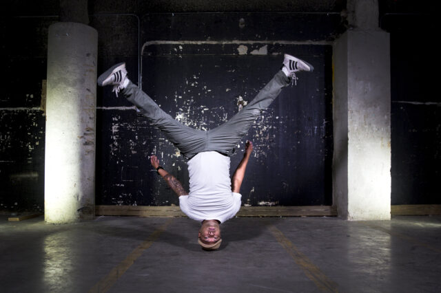 Dynamic Breakdancing Move In Urban Setting Wallpaper