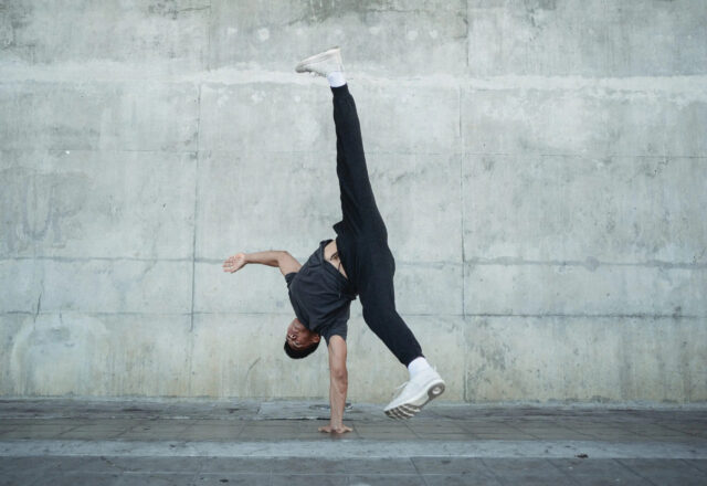 Dynamic Breakdancing Pose Against Concrete Wall Wallpaper