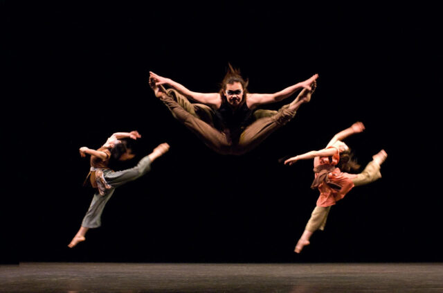 Dynamic Contemporary Dance Performance with High Energy Jumps on Dark Stage Background