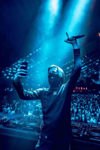 A DJ wearing a mask takes a selfie while performing in front of a lively crowd at a concert, HD Mobile Wallpaper