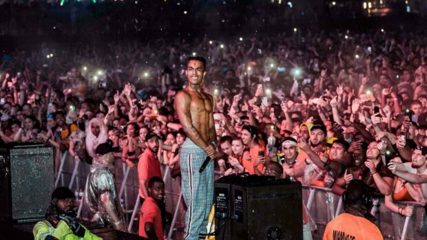 A shirtless performer holds a microphone on stage in front of an enthusiastic concert crowd using their phones, HD Desktop Wallpaper