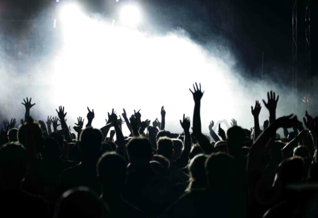 The crowd is raising their hands and enjoying the music during a concert with bright stage lights, 2K Desktop Wallpaper