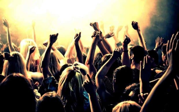 A lively audience raising their hands at a concert in warm lighting, HD Desktop Wallpaper