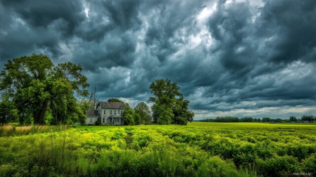 Farming wallpaper HD high quality, dramatic clouds hovering over a lush green farm surrounded by vibrant trees.