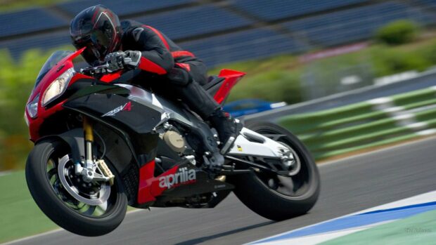 A rider on an Aprilia motorcycle is speeding around a race track, HD Desktop Wallpaper