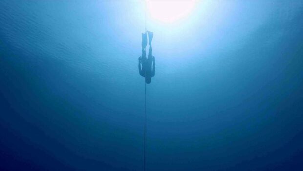 A freediver is descending along a rope into the deep blue ocean during a freediving session, 2K Desktop Wallpaper