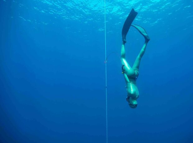 A freediver is descending deep underwater along a rope for freediving practice, HD Desktop Wallpaper