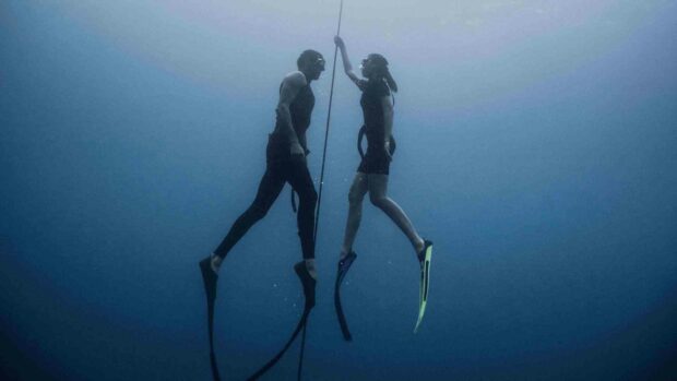 Two freedivers are underwater holding a rope during their freediving session in deep blue water, HD Desktop Wallpaper