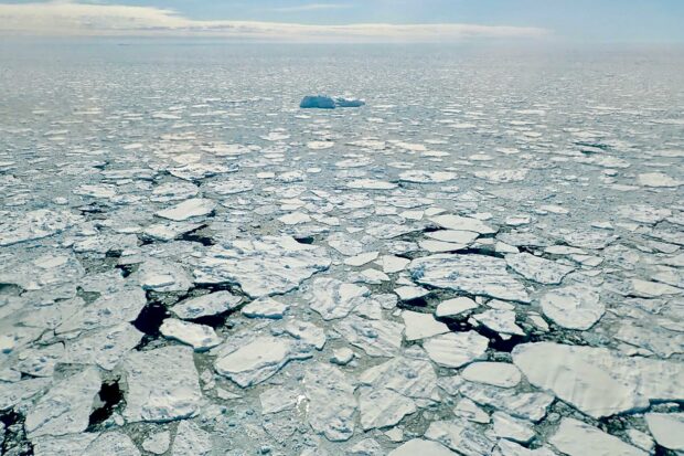 The image shows scattered ice floes on the Arctic ocean under a cloudy sky, HD Desktop Wallpaper