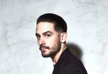 G Eazy stands confidently against a textured wall wearing a black suit, 4K Mobile Wallpaper