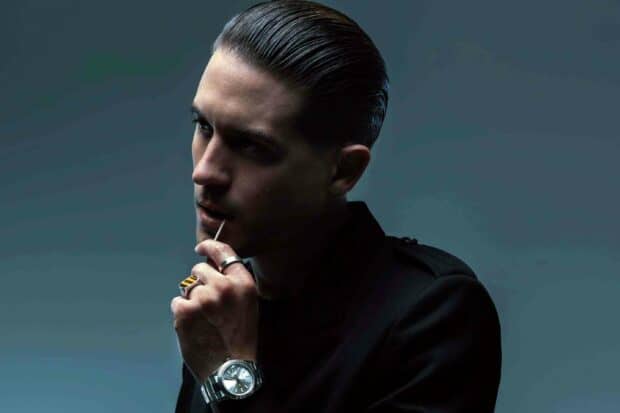 A thoughtful man with slicked back hair holds a toothpick near his lips in this G Eazy wallpapers, 2K Desktop Wallpaper