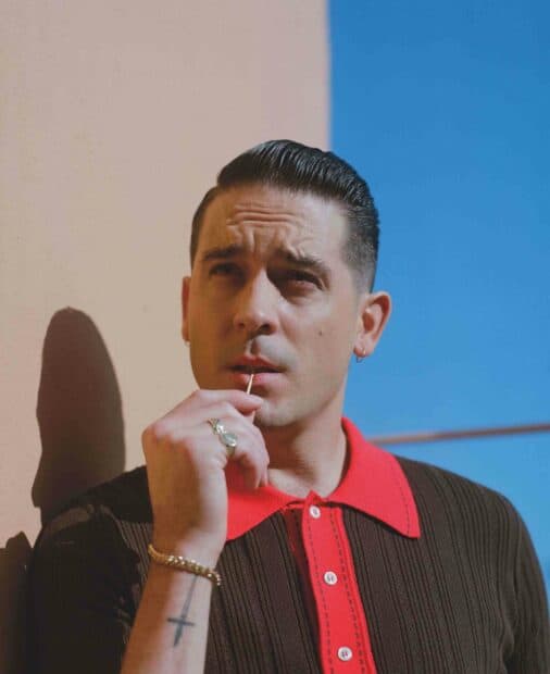A man wearing a red collared shirt contemplates while leaning against a beige wall, holding a toothpick near his mouth, G Eazy wallpapers, HD Desktop Wallpaper