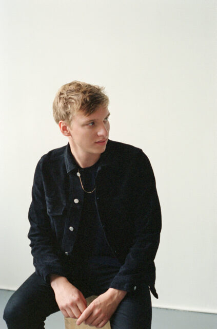George Ezra Casual Portrait Sitting Wearing Black Jacket Wallpaper