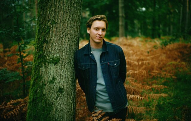 George Ezra Casual Pose in Forest Nature Background Wallpaper
