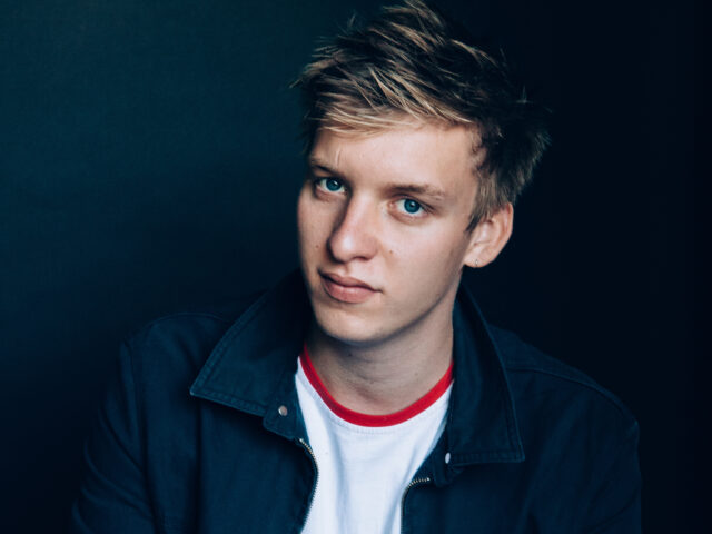 George Ezra Close Up Portrait Wallpaper with Blue Eyes and Casual Jacket