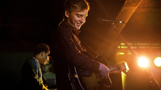 George Ezra Live Performance Playing Guitar with Warm Stage Lighting Wallpapers
