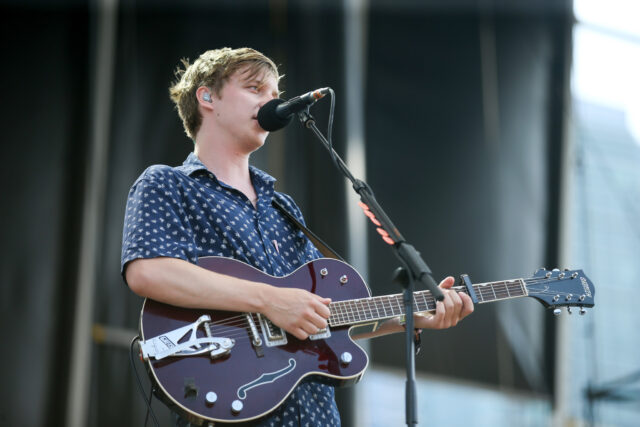George Ezra Performing Live on Stage Playing Guitar and Singing in Blue Shirt Wallpaper
