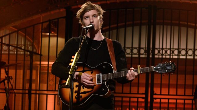 George Ezra Performing Live with Guitar on Stage Background George Ezra Wallpapers