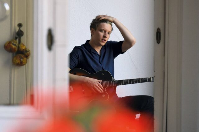 George Ezra Playing Guitar Casual Indoor Portrait Wallpaper