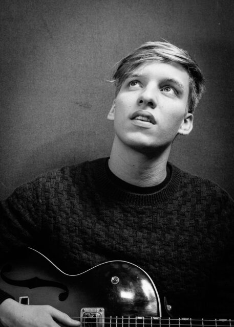 George Ezra holding guitar looking up black and white portrait wallpaper