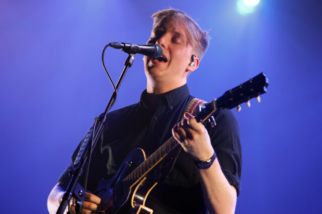 George Ezra live performance playing guitar and singing vibrant concert wallpaper