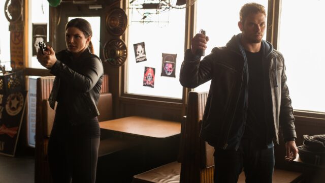Gina Carano action scene with armed standoff in dimly lit room wallpapers