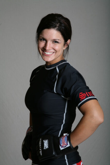 Gina Carano smiling in black sportswear and combat gloves MMA training wallpaper