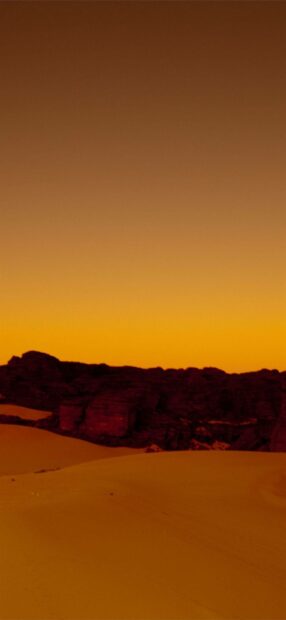 The golden desert landscape in Algeria features sand dunes and rocky formations under a clear sky, HD Mobile Wallpaper