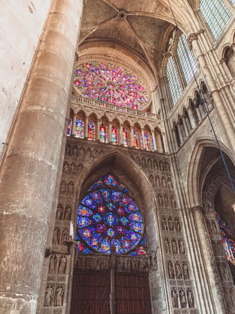 This cathedral interior showcases detailed stained glass rose windows and stone sculptures, 2K Mobile Wallpaper