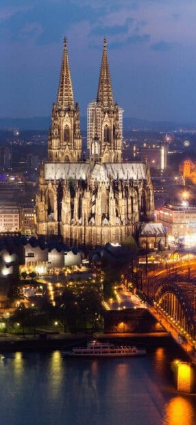 The cathedral displays stunning Gothic architecture illuminated against the city skyline at night, HD Mobile Wallpaper