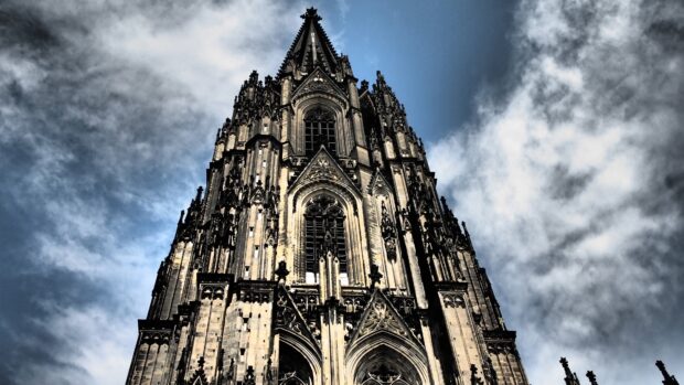 The cathedral features detailed Gothic architecture with pointed arches and towering spires against a cloudy sky, 4K Desktop Wallpaper