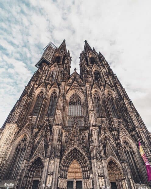 A detailed view of a gothic cathedral with intricate carvings under a cloudy sky, HD Mobile Wallpaper