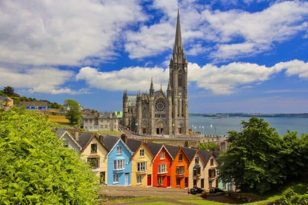 A gothic cathedral stands behind a row of colorful houses near the water, 2K Desktop Wallpaper