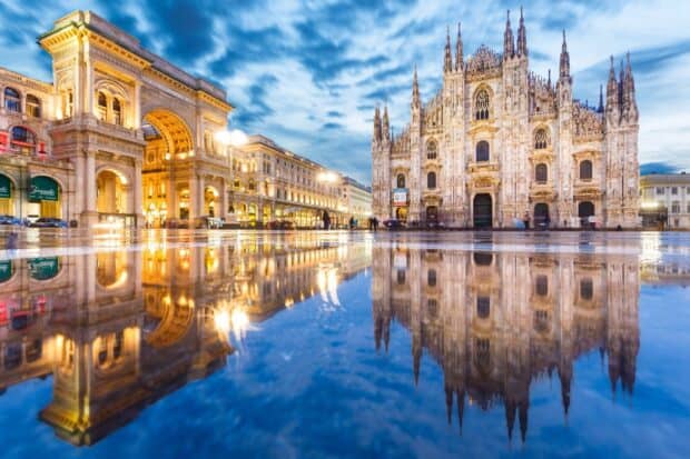 The cathedral shows intricate gothic architecture reflected in water under a cloudy sky, HD Desktop Wallpaper