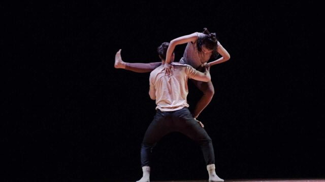 Graceful Contemporary Dance Couple Performing Artistic Movement on Black Background Wallpaper