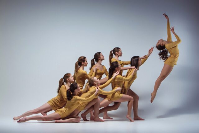 Graceful Contemporary Dance Group Performance in Yellow Leotards Artistic Wallpaper