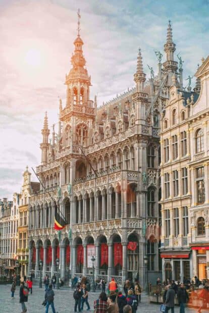 A lively crowd gathers in front of the historic Grand Place showcasing intricate gothic architecture in Brussels, HD Mobile Wallpaper