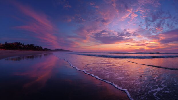 HD Desktop Backgrounds, a panoramic view of a serene beach at twilight, with gentle waves lapping at the shore.