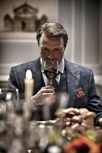Hannibal Mads Mikkelsen is holding a glass of red wine at a dining table, HD Phone Wallpaper