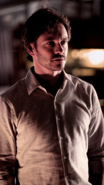 A thoughtful Hannibal Mads Mikkelsen stands in dim light wearing a white shirt, HD Mobile Wallpaper