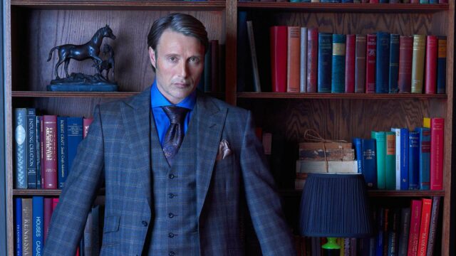 Hannibal TV Series Wallpaper Featuring Intense Character in Classic Suit by Bookshelf