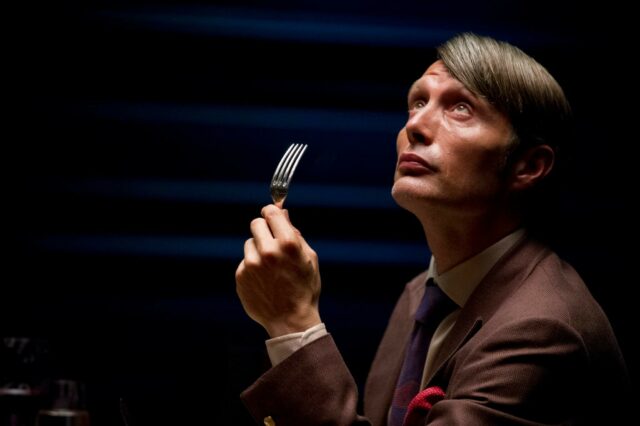 Hannibal TV Series Wallpaper Featuring Man Holding Fork in Dramatic Lighting