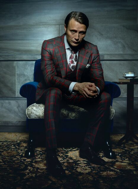 Hannibal TV Series Wallpaper Mads Mikkelsen Sitting in Checked Suit Dark Moody Interior