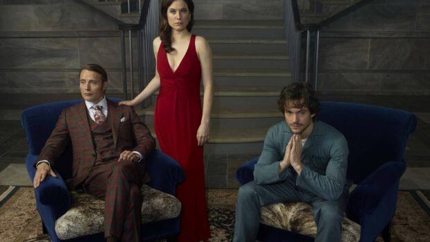 A man in a suit and a woman in a red dress pose with a seated man in casual clothes, HD Desktop Wallpaper