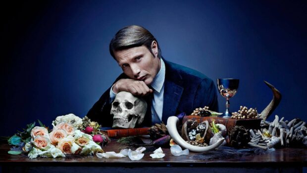 Hannibal Mads Mikkelsen poses with skull and flowers on dark table, HD Desktop Wallpaper