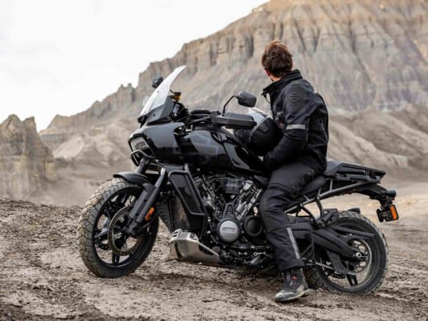 A rider in black gear sits on a Harley Davidson Pan America 1250 motorcycle in a rocky desert, HD Desktop Wallpaper