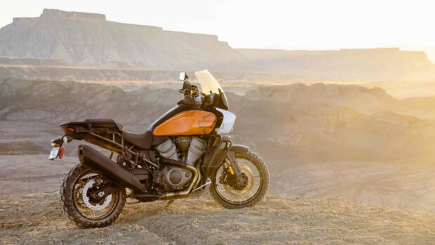 A Harley Davidson Pan America 1250 motorcycle parked on a rocky terrain during sunset, 4K Desktop Wallpaper